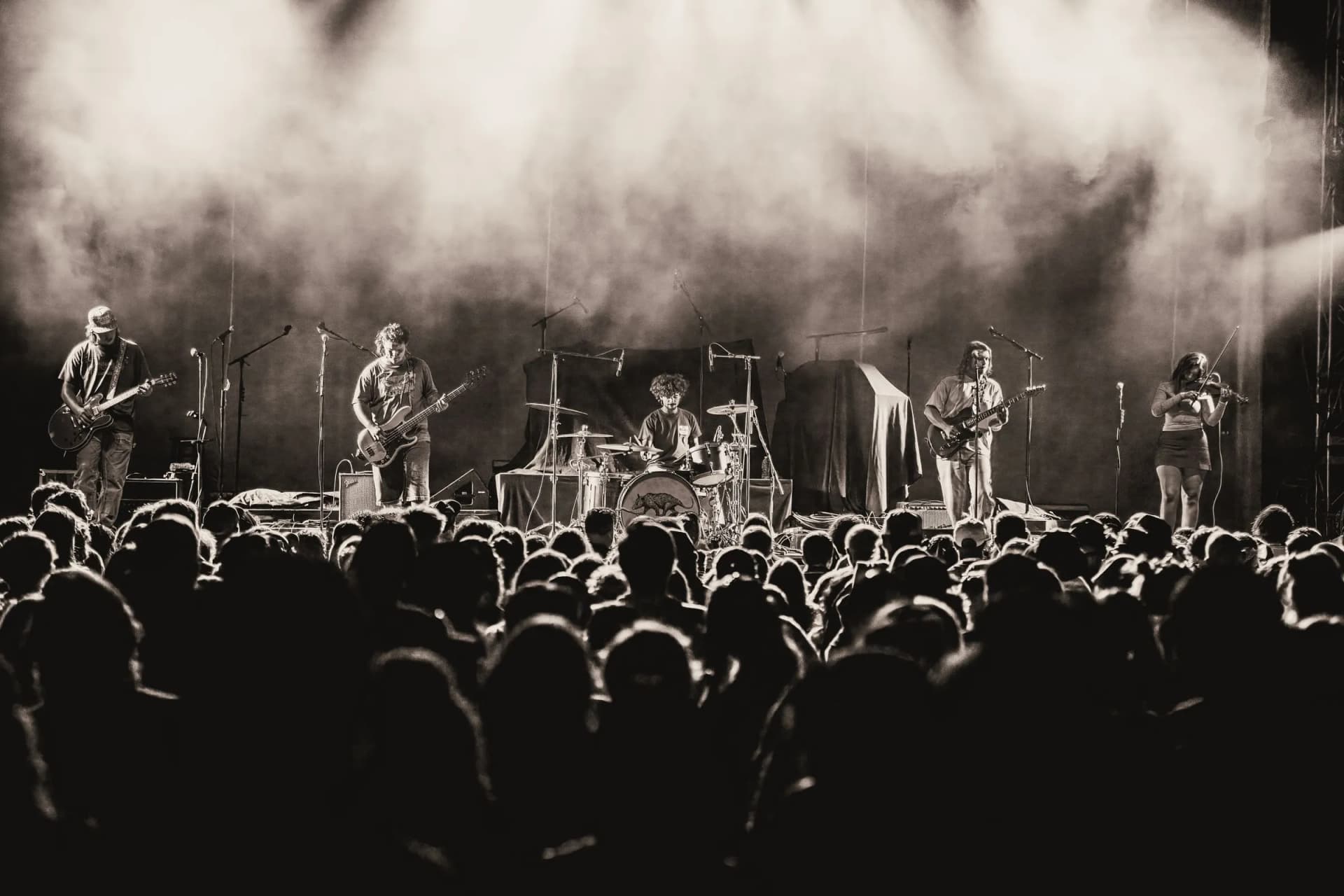 Black-and-white wide shot of Cigarettes @ Sunset on a hazy stage above a packed crowd