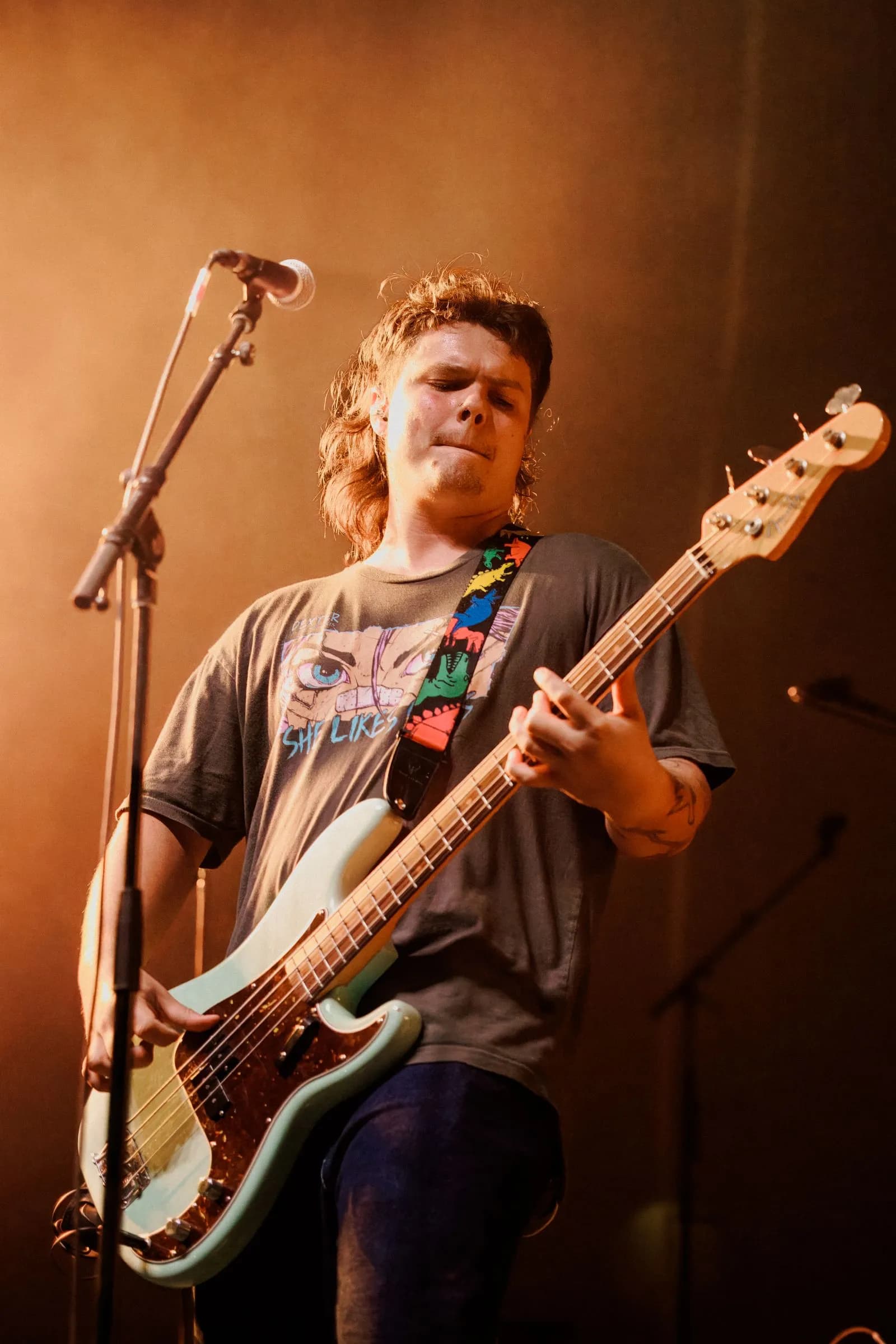 Cigarettes @ Sunset's bassist plays a cream bass with a rainbow strap under warm orange light