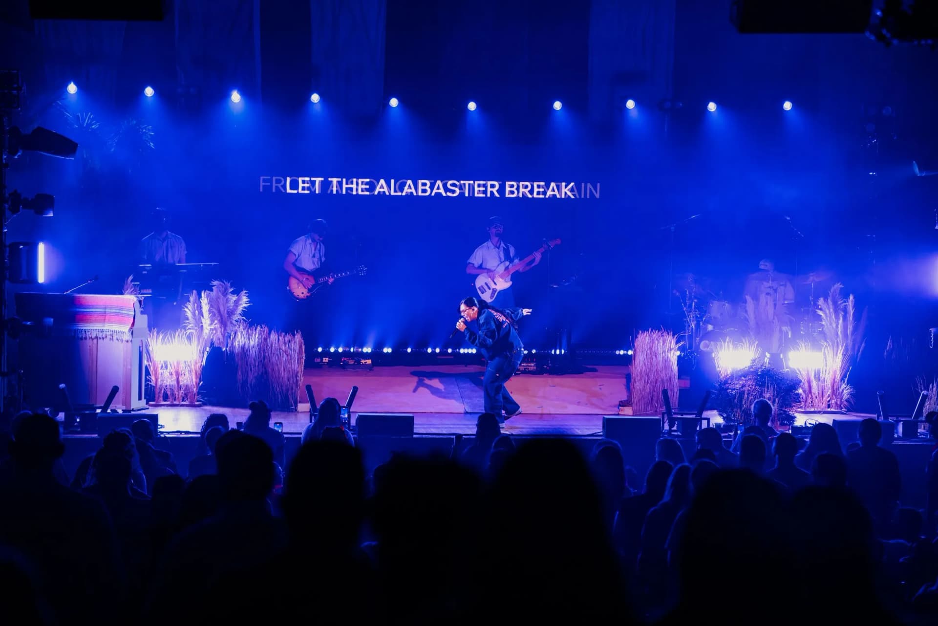 Wide shot of Lizzie Morgan's band on a blue-lit stage at Santander Performing Arts Center, with the lyric "Let the Alabaster Break" on screen